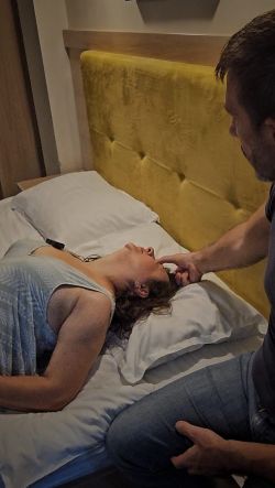 Calogero Grifasi guiding a female client lying down during an in-person regressive hypnosis session