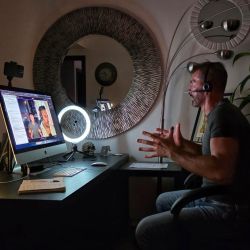 Calogero Grifasi conducting an online session or interview from his home office, with a monitor, ring light and headset