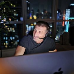 Calogero Grifasi conducting an online regressive hypnosis session from Dubai, with the city's illuminated skyline visible in the background